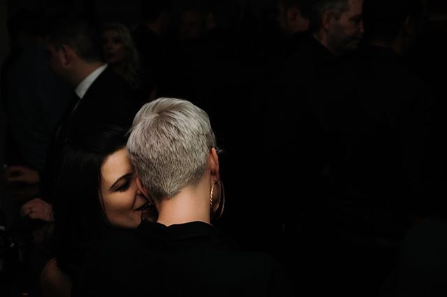 Two women share an intimate moment at a social gathering.