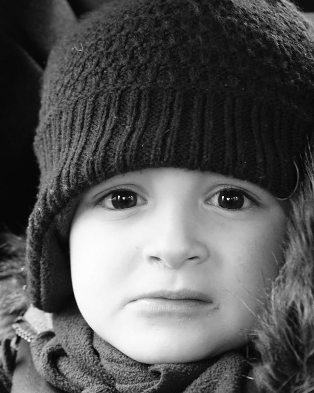A close-up portrait of a child wearing a winter hat looking directly at the camera.