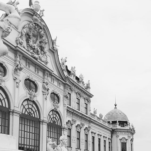 Detailed monochrome shot of the architecture of a historical building with intricate statues and domed roofs.