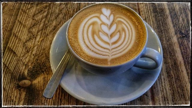 A delicious cup of cappuccino with latte art on a wooden table, perfect for a cafe culture or coffee break theme.