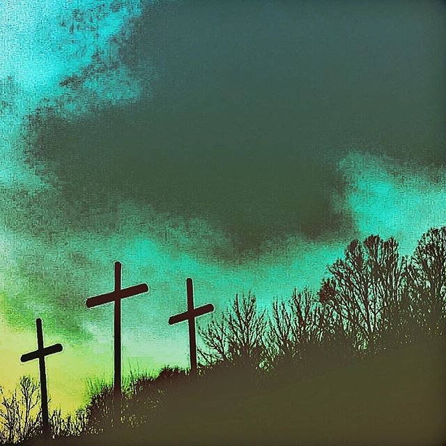Three crosses stand silhouetted on a hilltop against a moody sky, representing faith and spirituality.