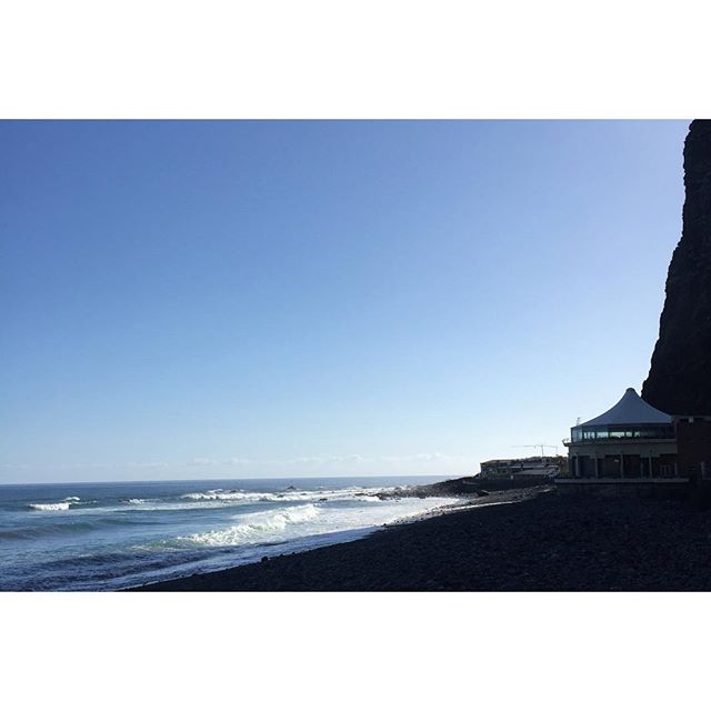 A tranquil beach scene with waves crashing on the shore and a building along the coastline, perfect for travel and tourism.