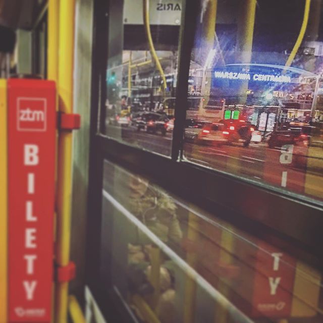Night view from inside a bus reflecting the Warszawa Centralna station sign, showcasing urban transportation.