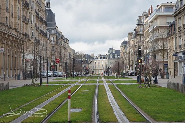 A cityscape view features tram tracks running through the center of a European city street.