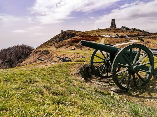 Cannons stand guard on a grassy hill overlooking the Shipka Monument, a memorial to Bulgarian and Russian soldiers.