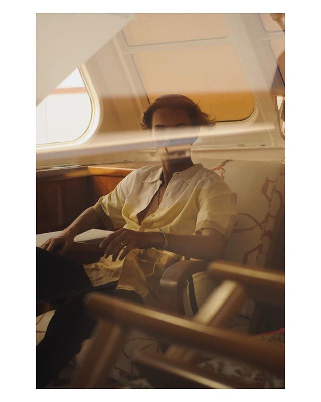 Man relaxes in a chair inside a boat with a warm, vintage aesthetic. 
