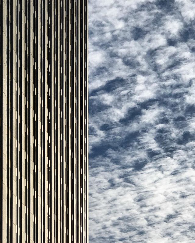 A modern building exterior meets a sky full of clouds, showcasing contemporary architecture and a peaceful urban atmosphere.