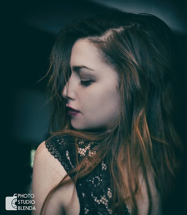 Portrait of a woman with brown hair and lace top looking down.