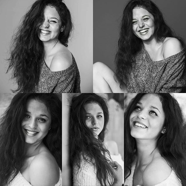 Black and white portrait of a smiling woman with curly hair in a sweater.