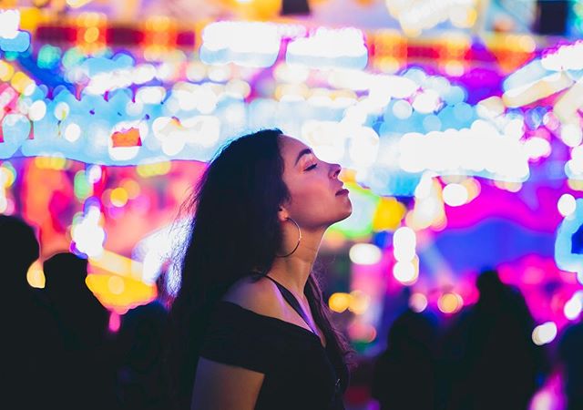 A woman looks upward with colorful bokeh lights behind her, capturing a moment of peace and serenity.