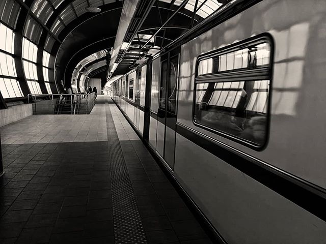 A sleek subway train waits at a modern station, showcasing urban mobility in a grayscale image.