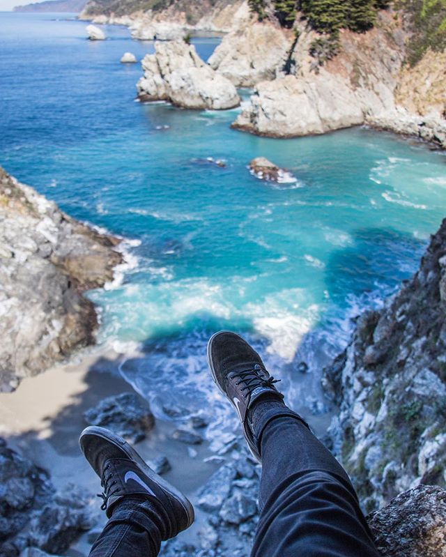 A person sits on a cliff edge overlooking a beautiful ocean view, showcasing the freedom of travel and a moment of serenity.