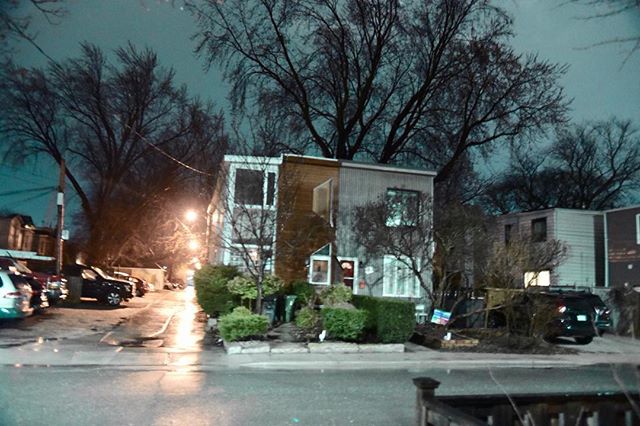 A nighttime street view with apartment buildings and bare trees. A quiet urban scene.