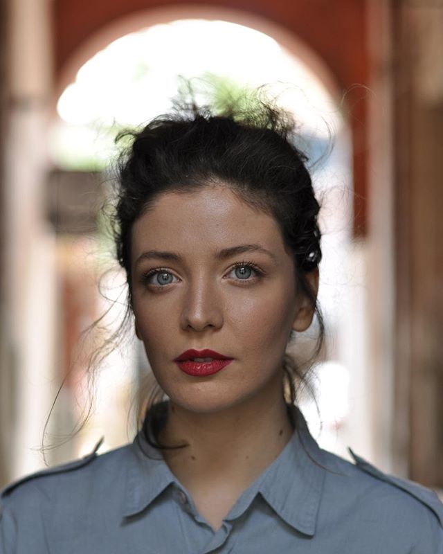 A captivating portrait of a woman with red lips, set against an architectural backdrop, perfect for beauty and fashion campaigns.