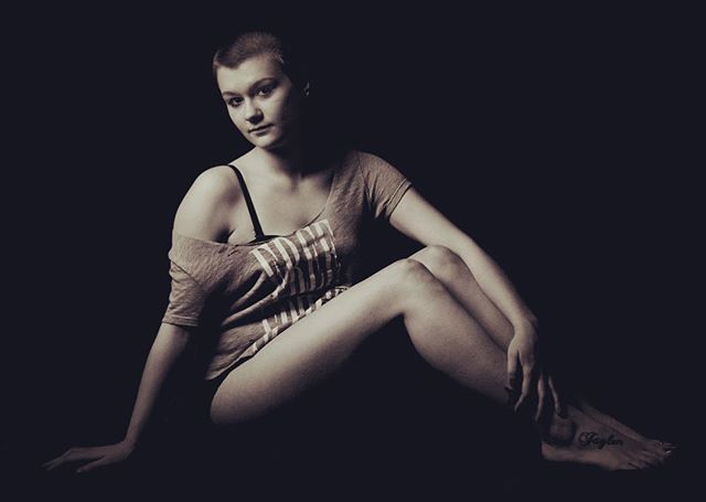 A woman with short hair poses in a studio with soft lighting for a portrait.
