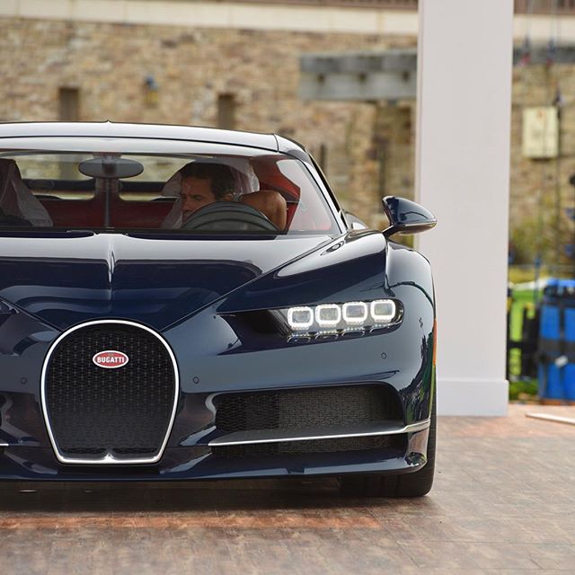 A close-up shot of a blue Bugatti Chiron with a driver inside, highlighting its luxurious design and performance.