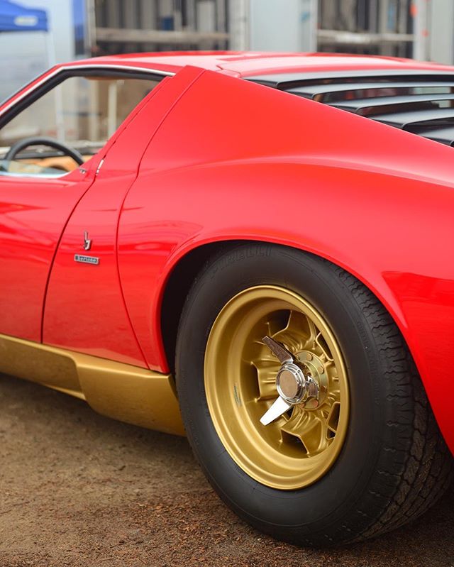 A vibrant red Lamborghini Miura showcases its iconic design and golden wheels, blending classic elegance with vintage charm.