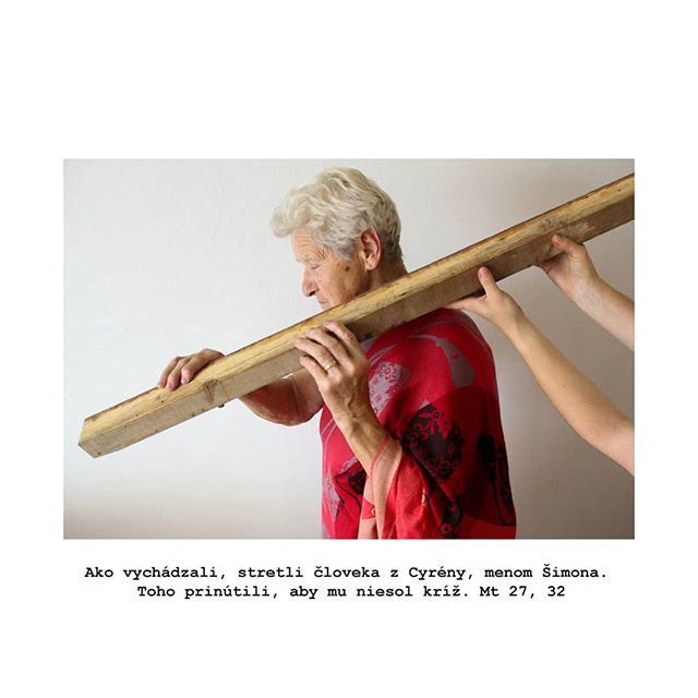 An elderly woman with short hair carries a wooden beam, symbolizing faith and burden-sharing.