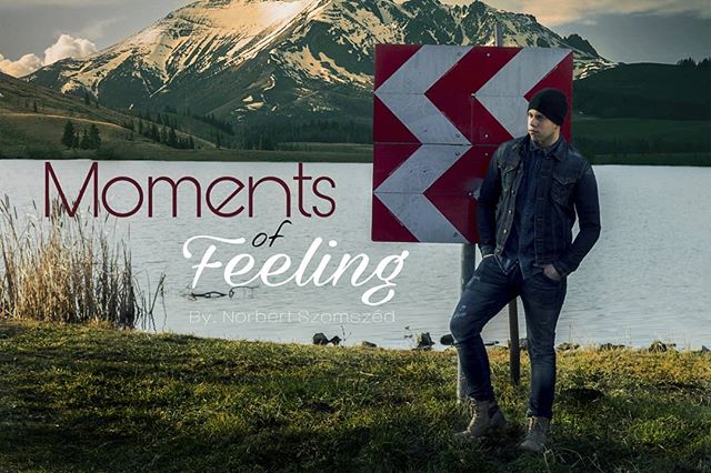 A man poses near a lake and mountain, exuding style and calm in a scenic outdoor setting. 