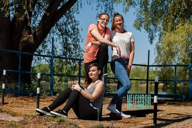 Three cheerful friends pose outdoors in a park setting, capturing a candid lifestyle moment.