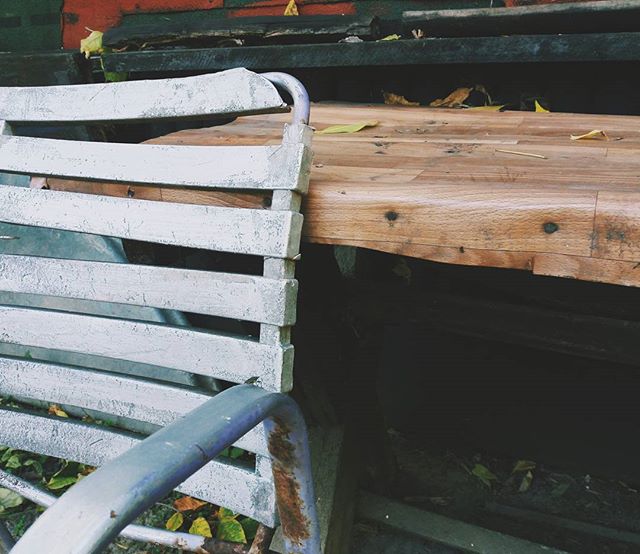 A close-up of a rustic bench with a wooden table. Perfect for a calm garden design concept.