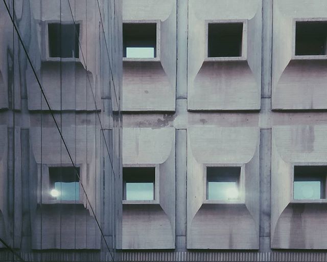 A modern building facade with geometric windows, showcasing minimalist urban architecture and design.