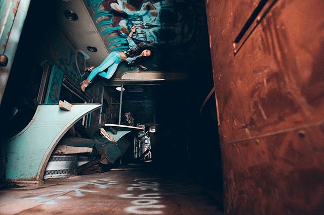 A woman poses in an abandoned graffiti-covered train car, offering an edgy and unique urban exploration concept.