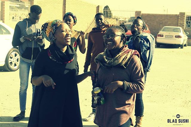 A group of friends laugh and enjoy each other's company outside on a sunny day.
