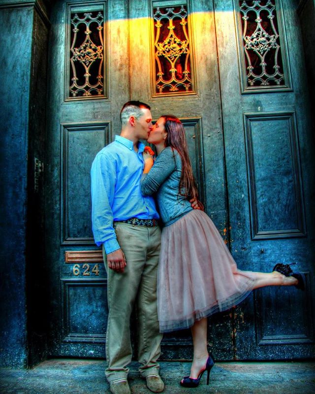 A couple shares a kiss in front of an old blue door, capturing an intimate moment of love and connection.