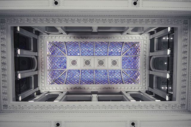 An ornate ceiling in a building showcases intricate architectural details and a calming blue-and-white design.