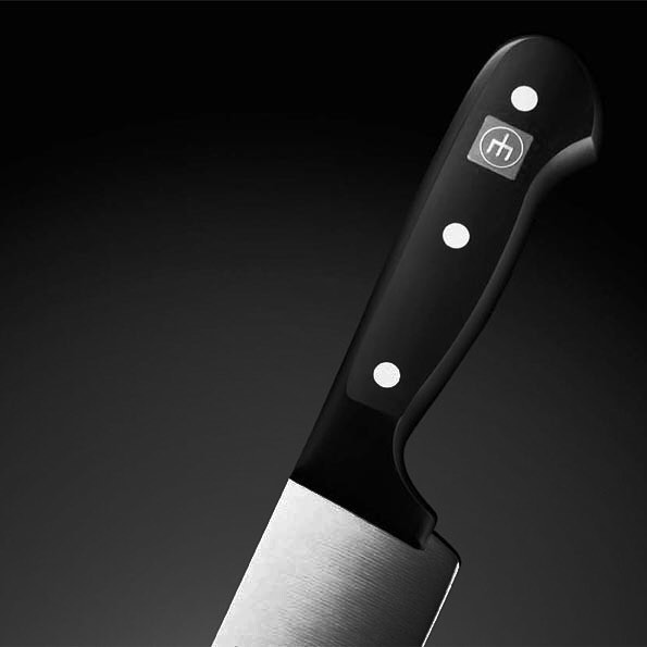 Close-up of a modern chef's knife against a dark background, ideal for culinary and lifestyle advertising.