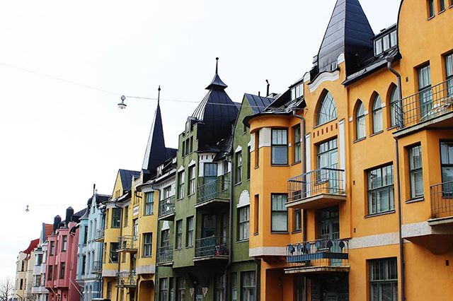 A row of colorful, vintage buildings lines a European city street under a bright sky, showcasing unique urban architecture.