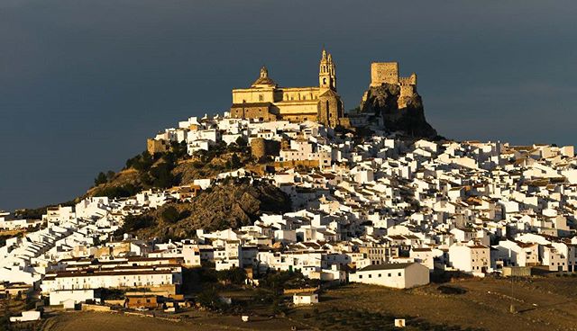 Scenic view of Zahara de la Sierra, a white-washed town with a castle and church on a hilltop in Andalusia, Spain.