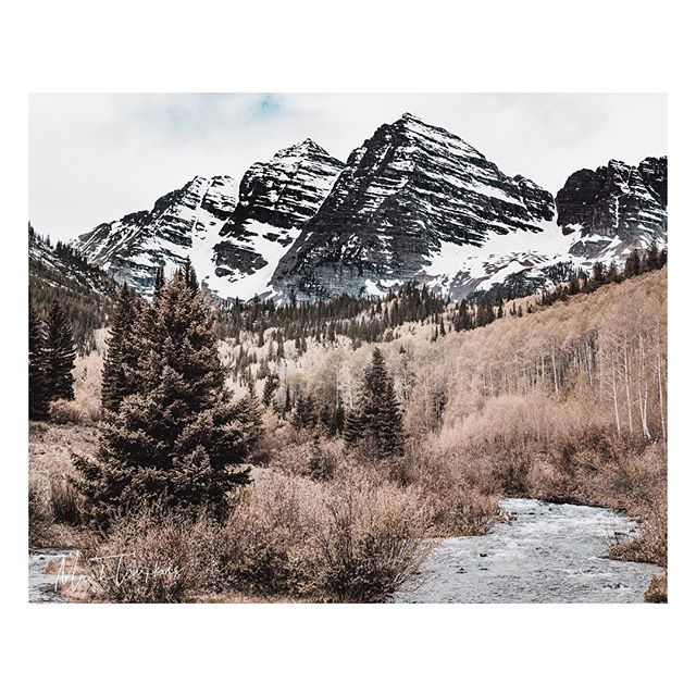 A scenic view of snow-capped mountains, forests, and a flowing river.