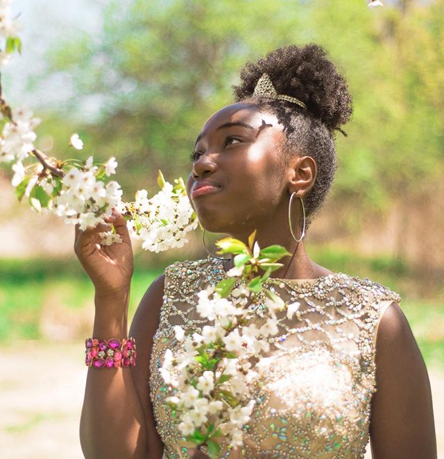 A young woman gazes at cherry blossoms, radiating calm and beauty in a serene garden setting.