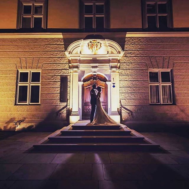 A bride and groom share a kiss at the entrance of a building.