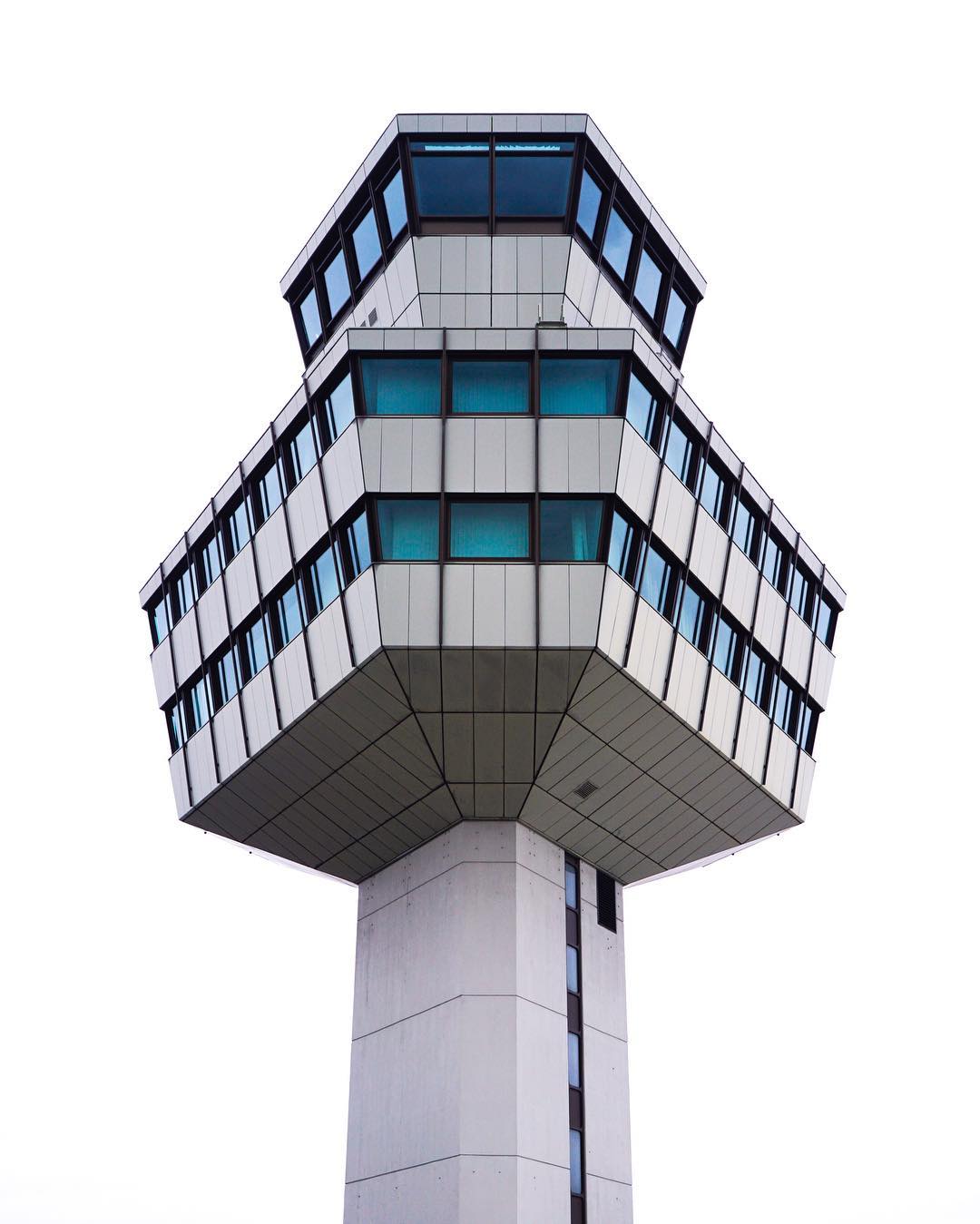 A modern air traffic control tower stands against a clear sky, symbolizing airport infrastructure and travel.