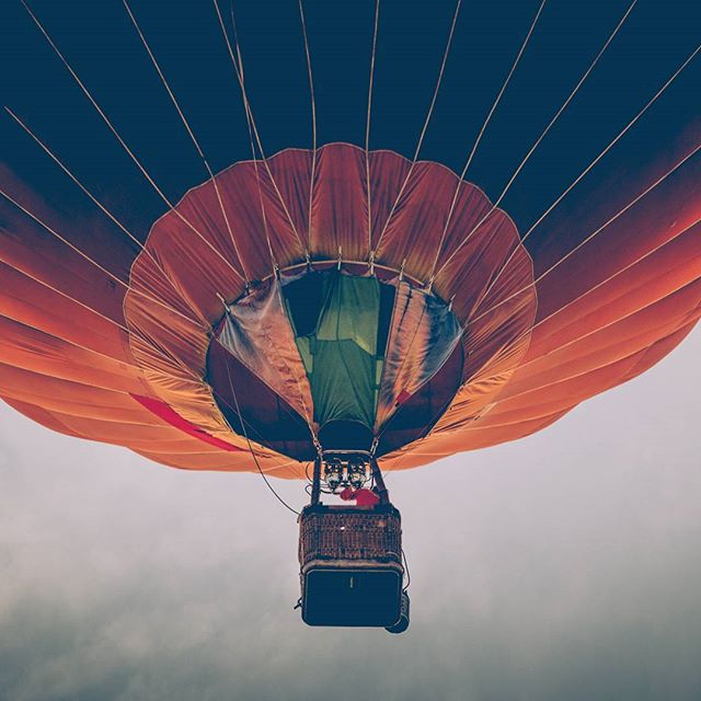 A low-angle shot shows a colorful hot air balloon against a cloudy sky, emphasizing adventure and peaceful travel.