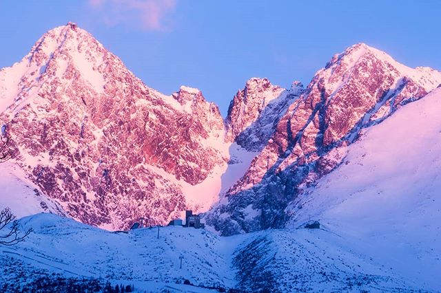 Snow-capped mountains at dusk create a serene winter landscape. Pastel colors paint the sky and peaks with a soft, dreamy light.