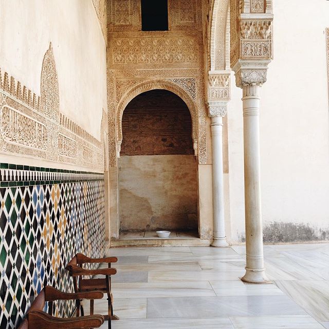 An ornate courtyard features intricate tilework, arched doorways, and slender columns, showcasing classic architectural details.