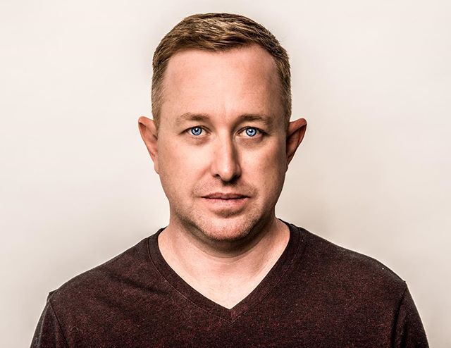 A man with blue eyes poses in a studio headshot. Ideal for professional profiles and business content.