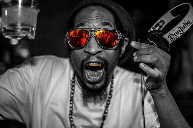 A vibrant man with sunglasses and gold teeth enjoys a party. 