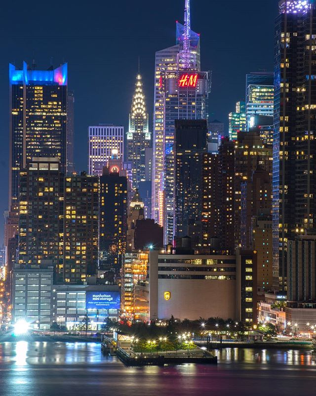Night cityscape of Manhattan with illuminated skyscrapers reflecting on the water. New York City's vibrant urban skyline.