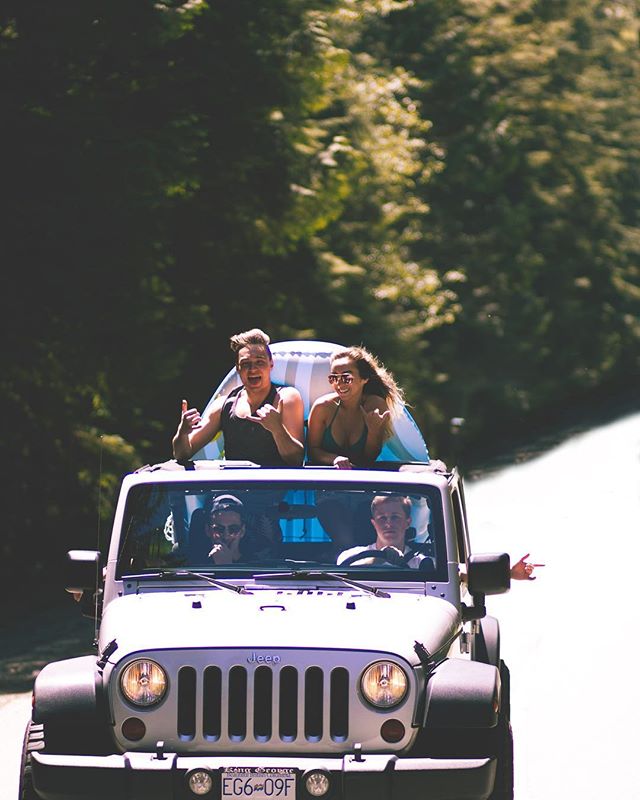 Four friends enjoy a fun road trip in an open-top Jeep through a scenic forest, capturing the essence of summer adventure.