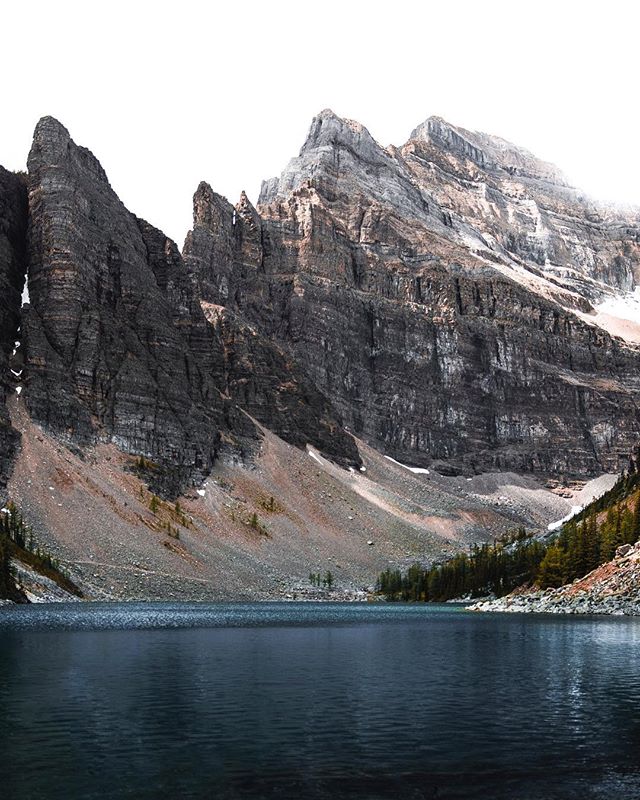A tranquil lake nestled amidst towering, rocky mountains creates a serene and breathtaking natural landscape.