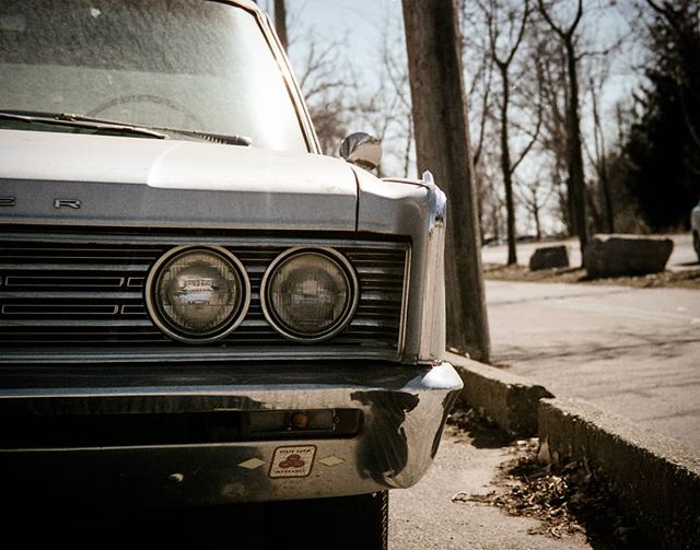 A vintage car's front end is featured in a close-up shot, highlighting its classic grille and headlights.
