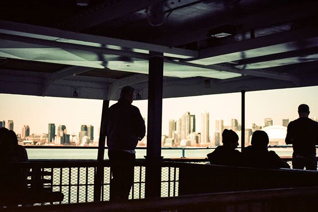 People on a ferry view the city skyline in a tranquil, muted tone, offering a scenic urban escape.