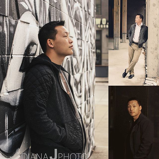 An Asian man poses in an urban alley with graffiti. He is wearing a jacket.
