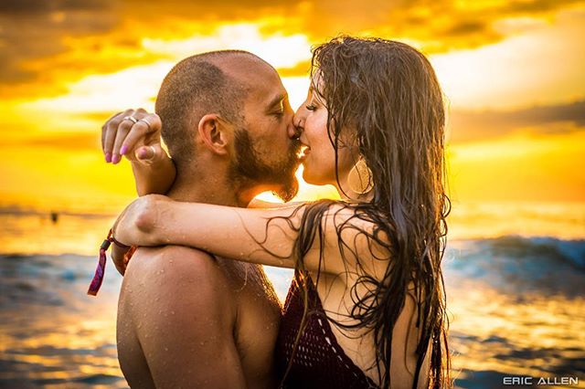 A couple shares an intimate kiss on a sun-kissed beach at sunset, embodying romance and connection.