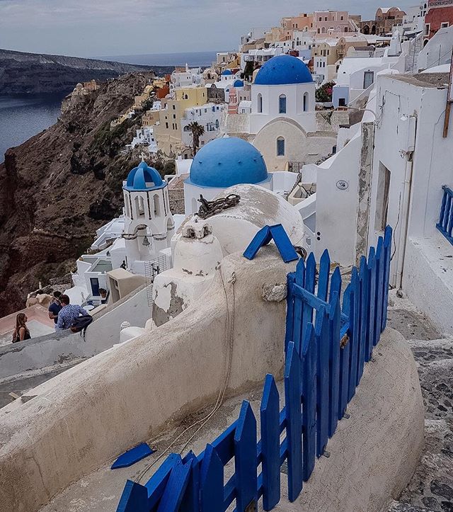 Picturesque Santorini village featuring iconic blue domes and whitewashed buildings on a scenic cliffside overlooking the Aegean Sea.